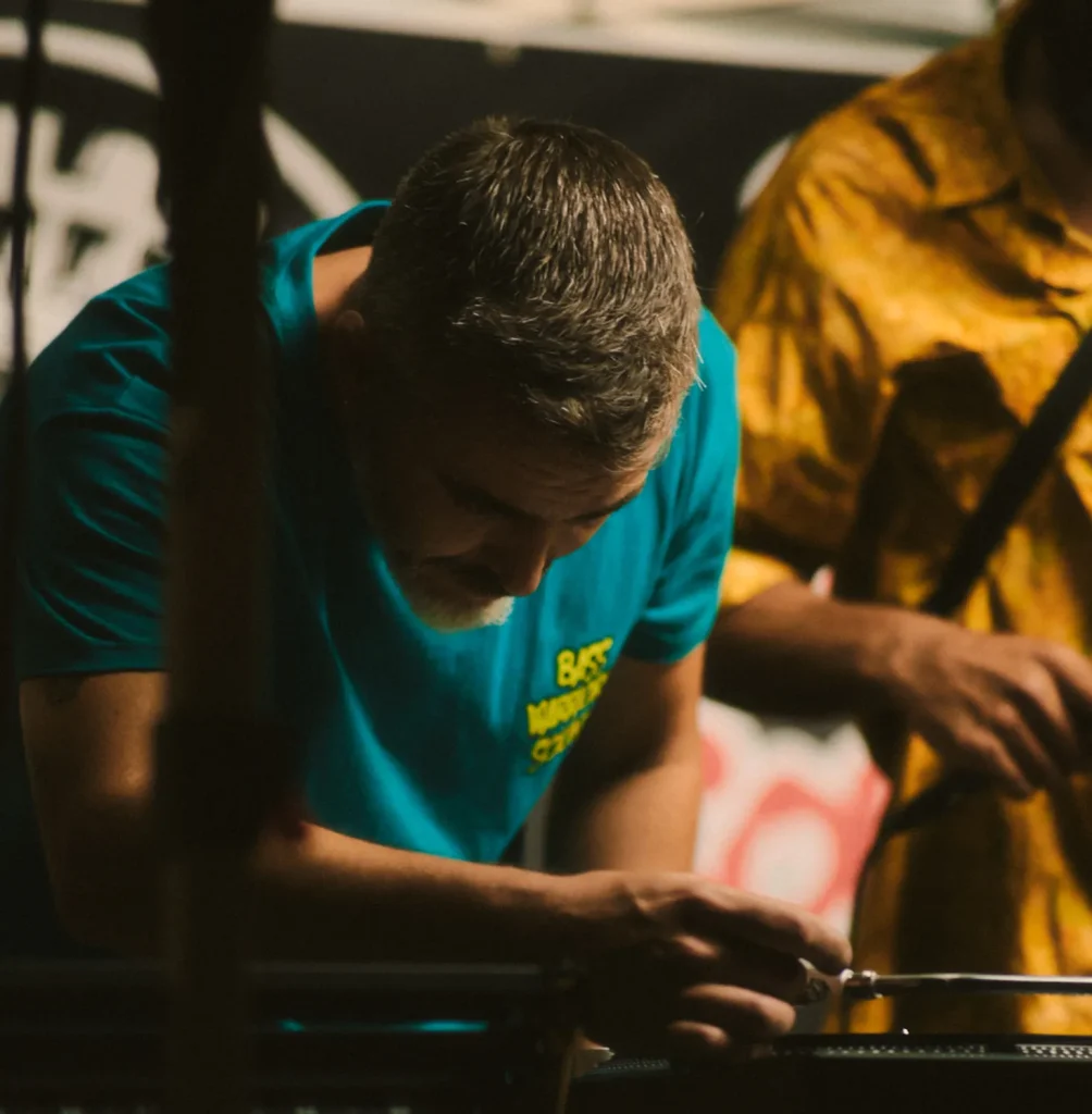 Close-up of a DJ's hands mixing music on a turntable, with another person visible in the background.