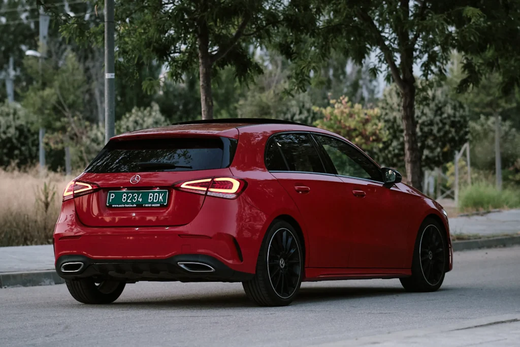 Red Mercedes-Benz A-Class Hatchback rear three-quarter angle on road, showcasing taillights and twin exhaust pipes.