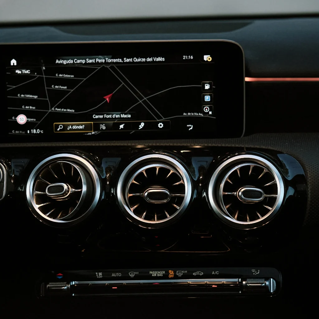Close-up detail of Mercedes MBUX system screen showing navigation map and climate control panel with illuminated turbine air vents.