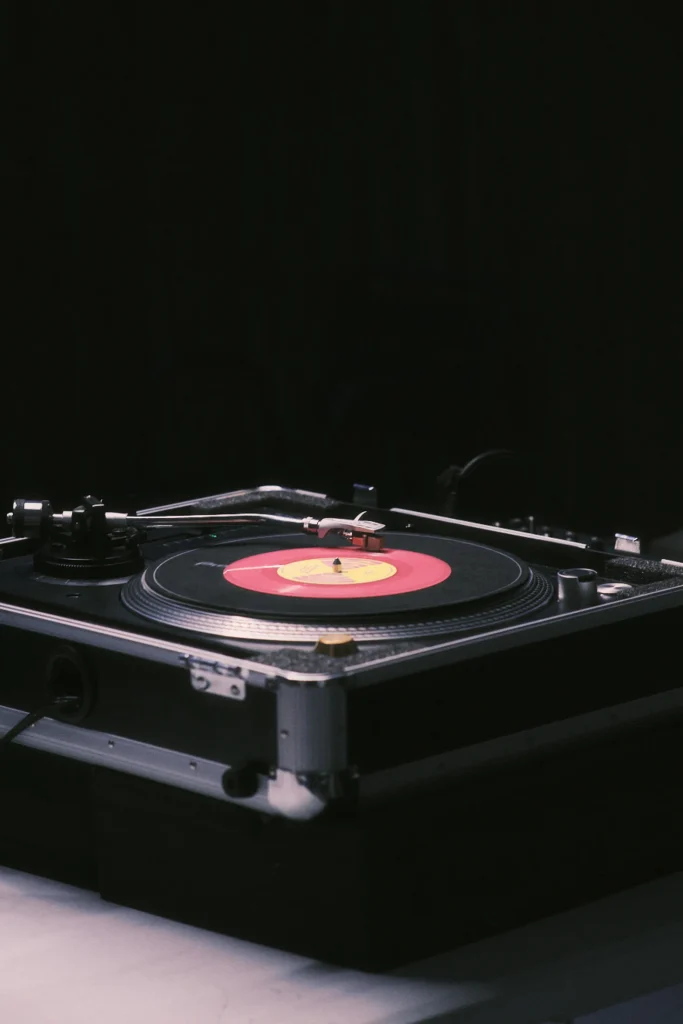 Dark, close-up shot of a red vinyl record playing on a professional turntable in its protective flight case.