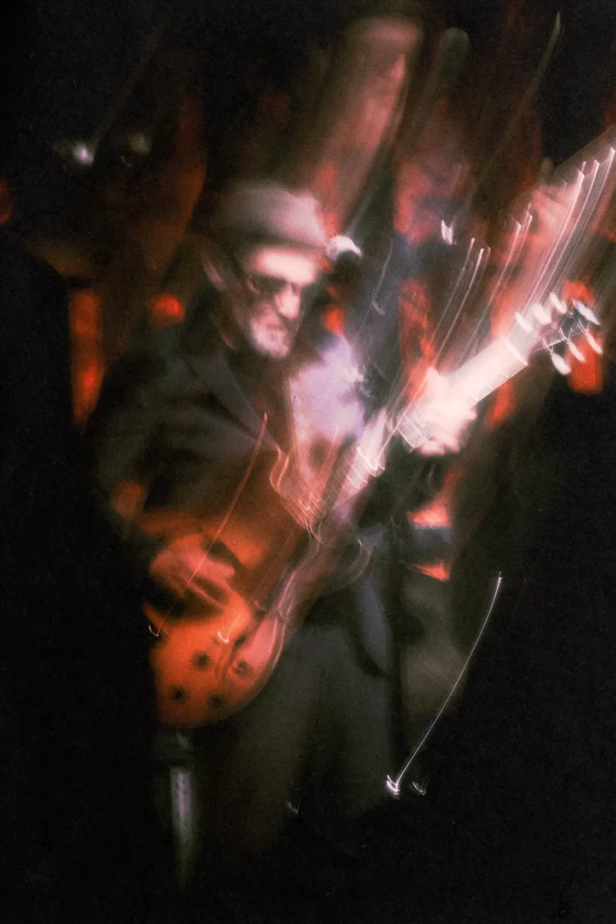 Abstract, dark, and moody lifestyle portrait of a jazz musician playing guitar at a cultural event, capturing movement and the nightlife atmosphere for creative editorial content