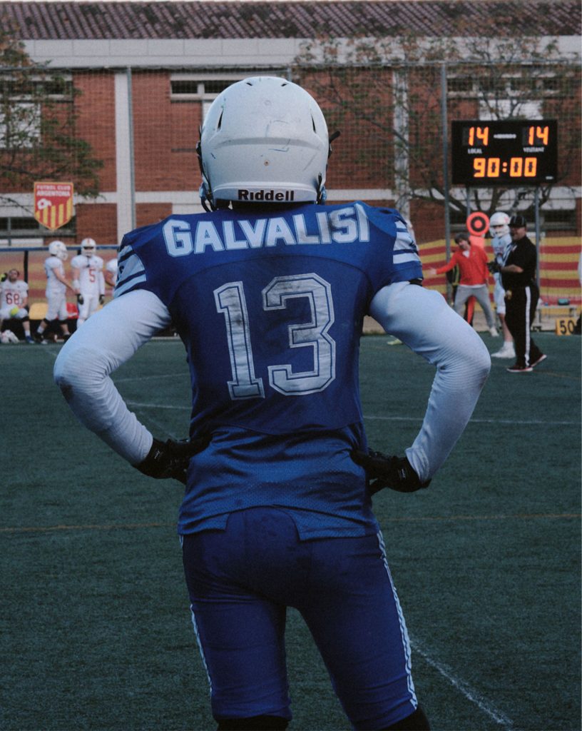 Back view portrait of American football player (Galvalis 13) on the sideline, showing concentration and body language of intensity.