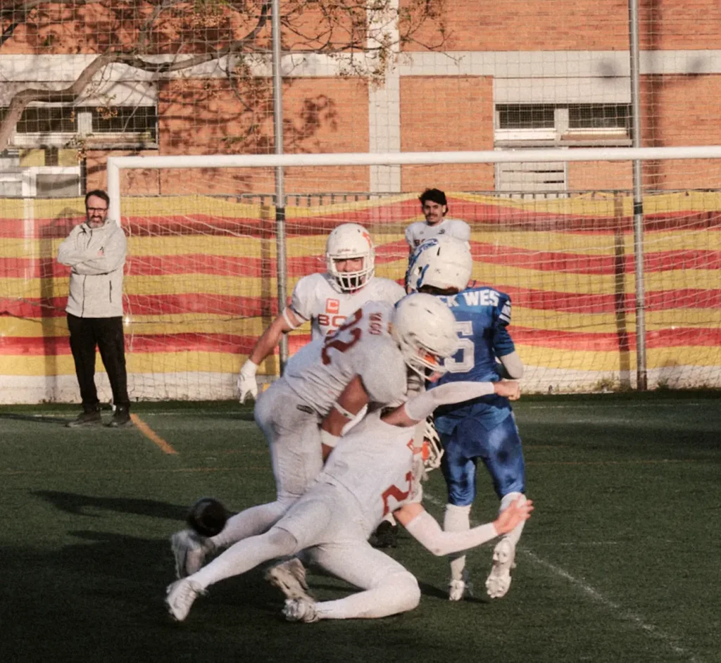 High-impact tackle photography during an American football game, capturing collision and intensity under fading light.