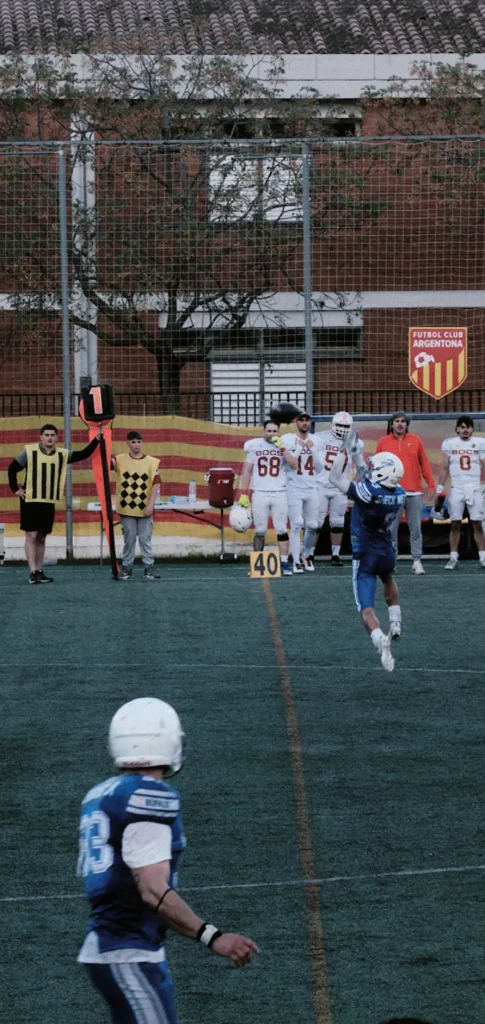 Wide vertical shot of a player catching a punt or kick, demonstrating focus and verticality on the field goal line.