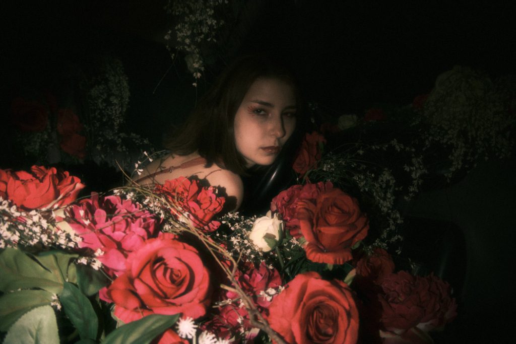 Close-up of the Burnout protagonist's emotional climax, with red roses filling the car interior in a dark setting