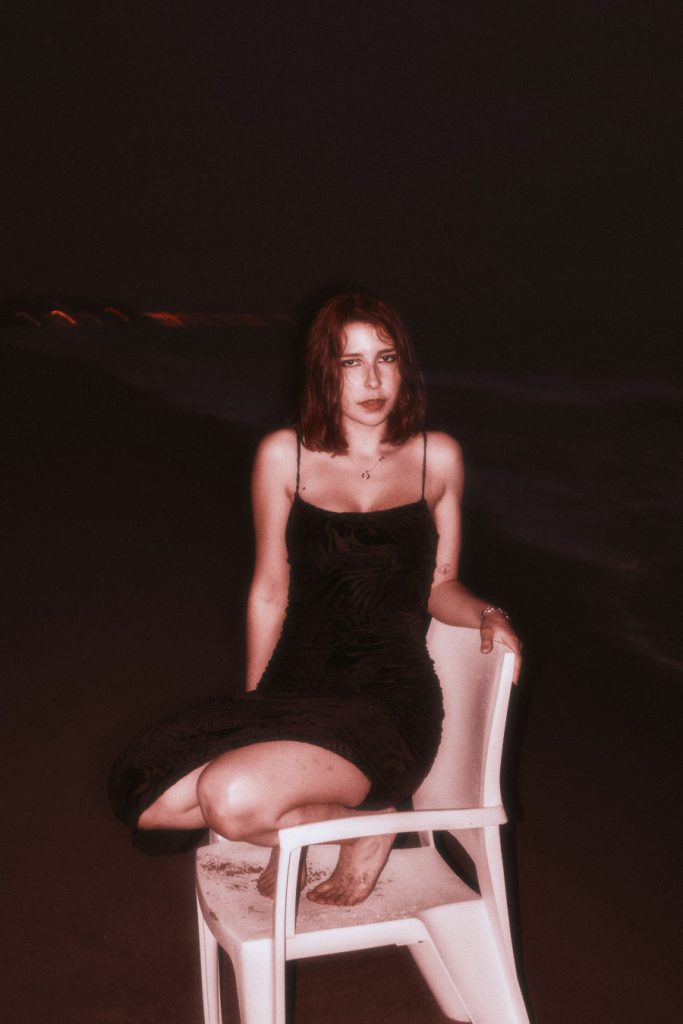 The Burnout protagonist sitting on a white chair on a reddish beach, with subtle waves in the background
