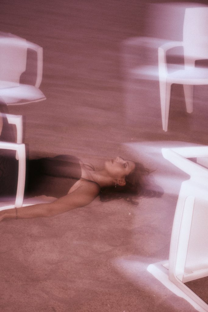Close-up of the Burnout protagonist seemingly trapped among chairs on a reddish beach, with surreal motion blur.