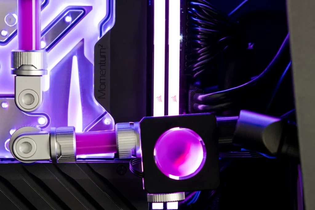 Close-up of a Custom PC watercooling loop with purple coolant, silver fittings, and Corsair RGB RAM modules in a high-end gaming build.