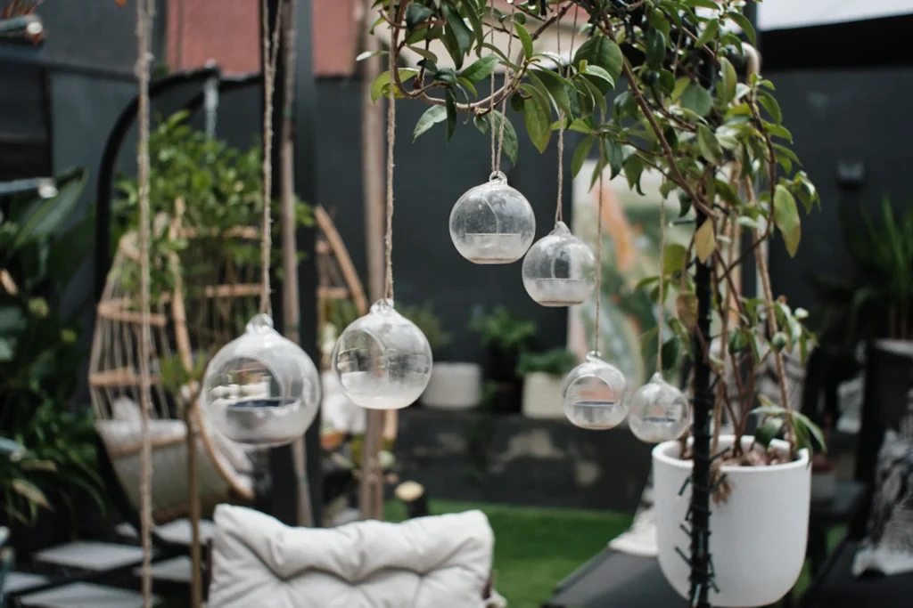 detail shot of hanging glass candles and potted plants in a modern outdoor patio, emphasizing nature-inspired home decor and architectural elements