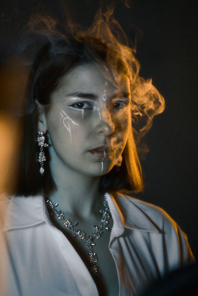 Dramatic beauty portrait with artistic makeup and smoke effects, highlighting luxury jewellery and cinematic lighting for editorial features