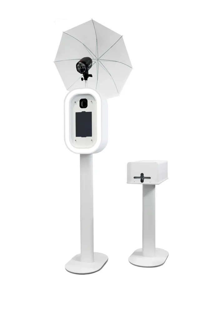 Modern white Smart Photobooth with a light-up ring, screen, and an external white photography umbrella/softbox for optimal lighting.