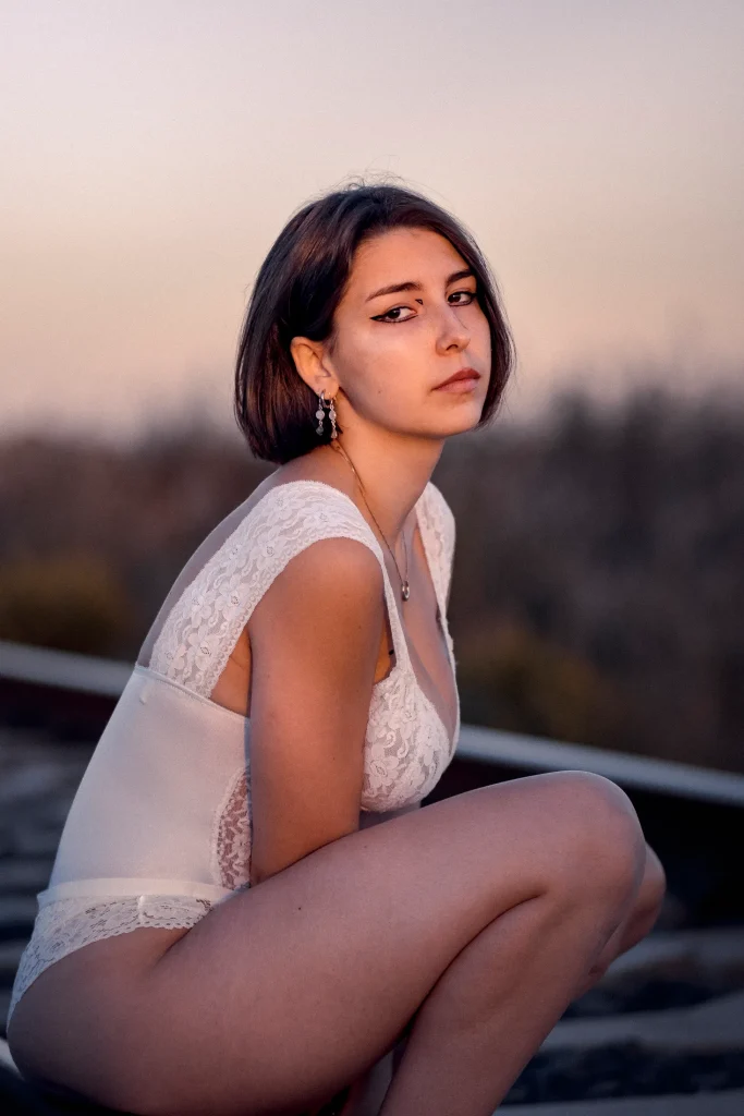 Low-key conceptual boudoir photo of a woman's legs and body framed by the seat of a vintage train, highlighting texture and composition.